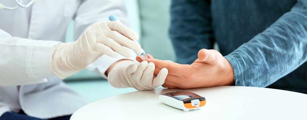 uma pessoa com luvas fazendo um exame de sangue - Diabete Mellitus