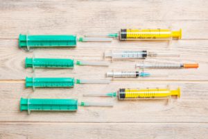 Vista superior de muitas seringas e uma seringa de insulina preparada para injeção em fundo de madeira. Conceito de tratamento com espaço de cópia.