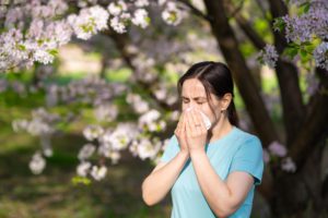mulher com a mão no nariz, com alergia respiratória