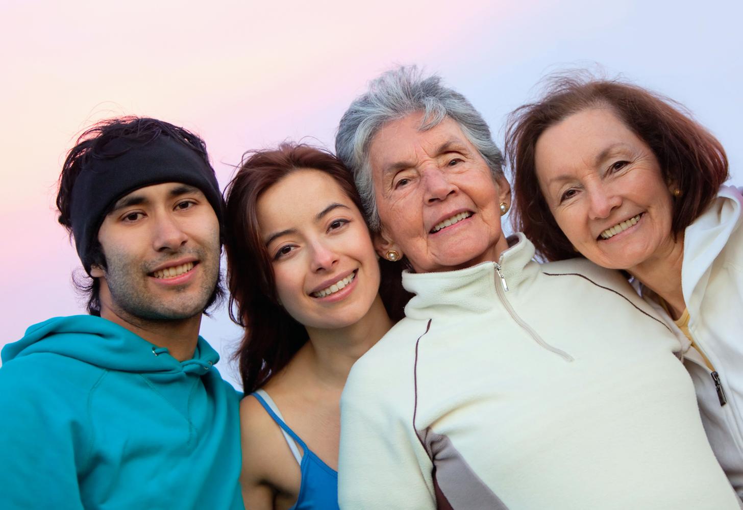 Four people smiling together outdoors.