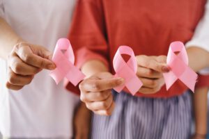 Hands holding pink cancer awareness ribbons