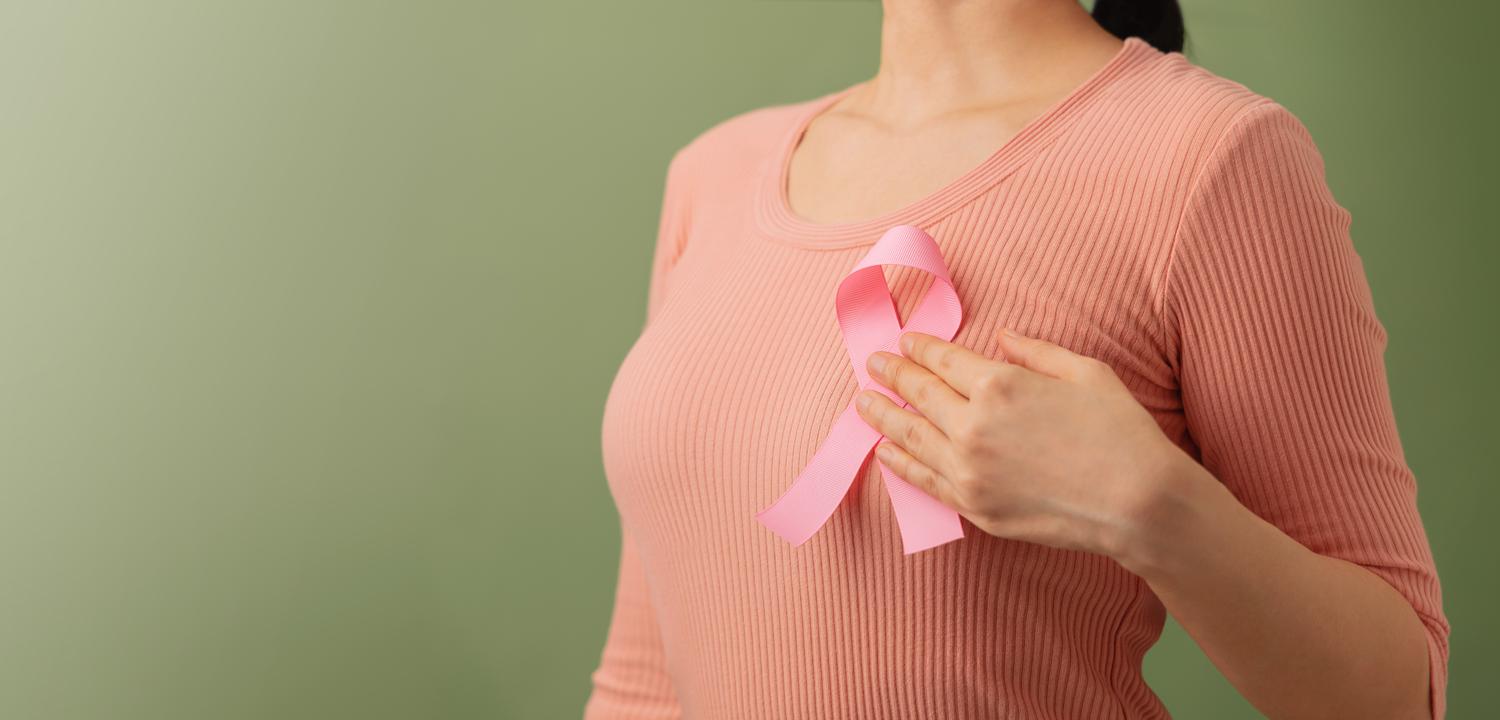 Woman holding pink ribbon on shirt