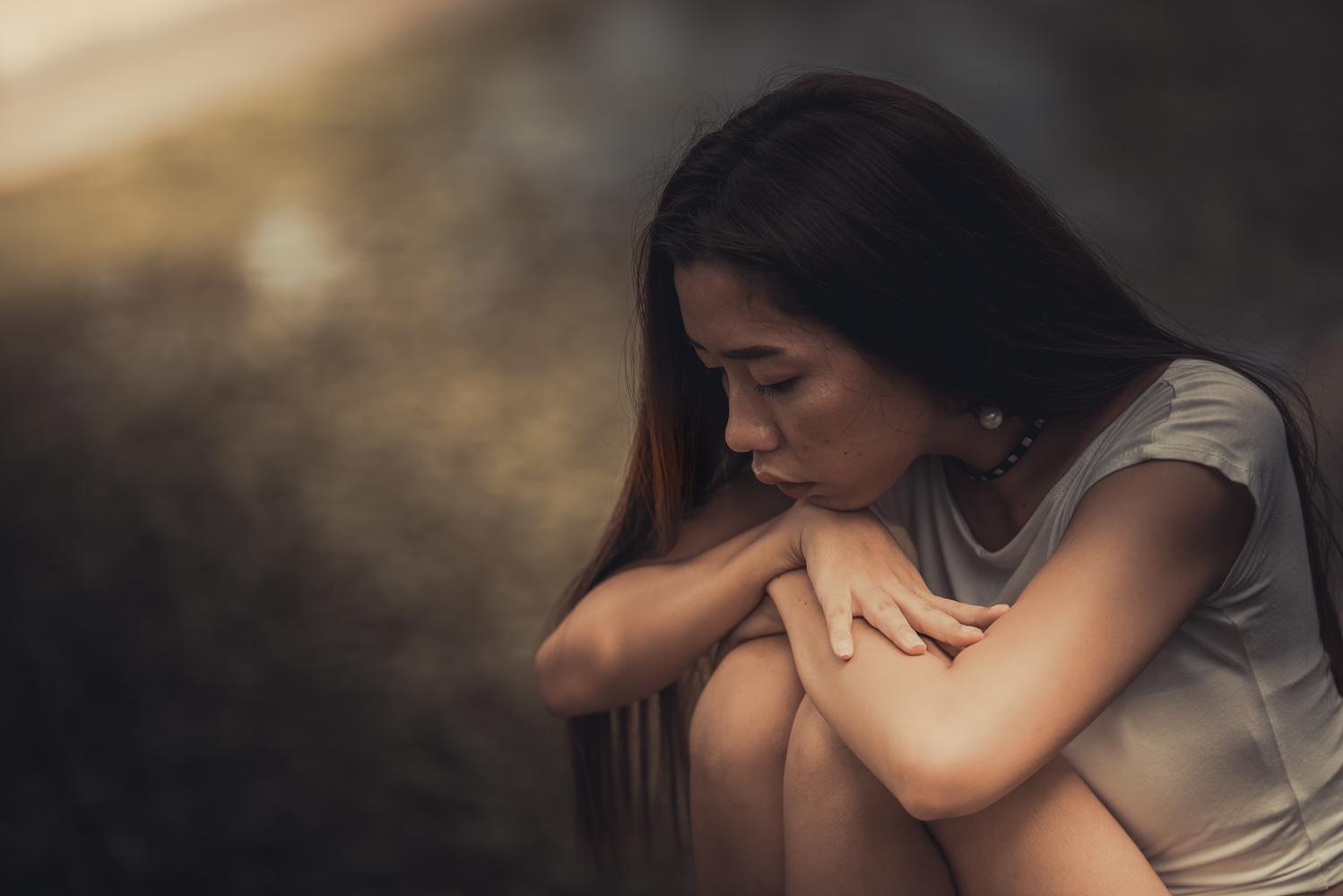 Woman sitting, looking contemplative and sad.