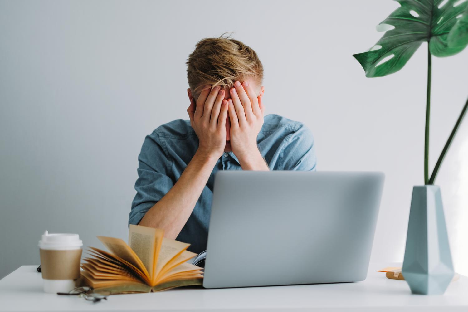 Stressed person with laptop and book
